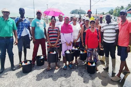 Residents, accompanied by Preparedness and Response Manager Major Lakshman Persaud and councillors, pose with their hampers 
