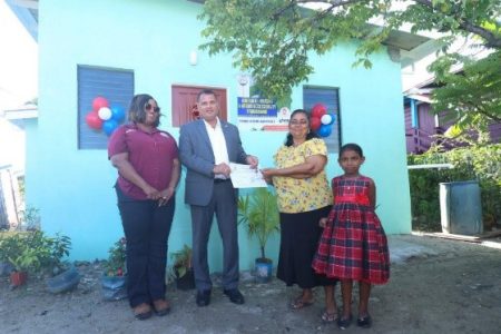 Minister of Housing and Water Collin Croal (2nd left) and Deputy Director of Community Development, Donell Bess-Bascom (left), handing over the keys to Sonita and one of her granddaughters.