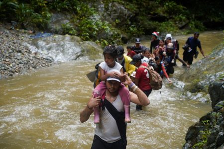FILE PHOTO: A migrant carries a child as they along with others continue their journey to the U.S. border, in Acandi, Colombia July 9, 2023. REUTERS/Adri Salido