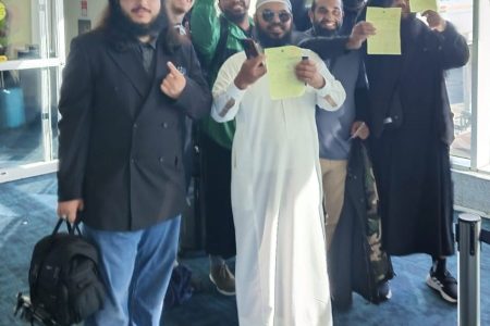Islamic Scholar Sheik Uthmaan Ibn Farooq, centre, and his group show their entry rejection papers at the Piarco International Airport on Sunday.