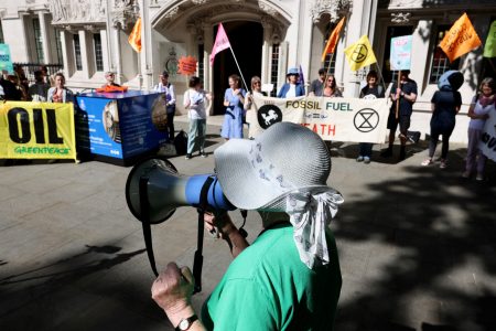 A person uses a megaphone as climate activists await a ruling on whether planning permission granted for oil wells in southern England was lawful, outside the Supreme Court in London, Britain, June 20, 2024. REUTERS/Kevin Coombs