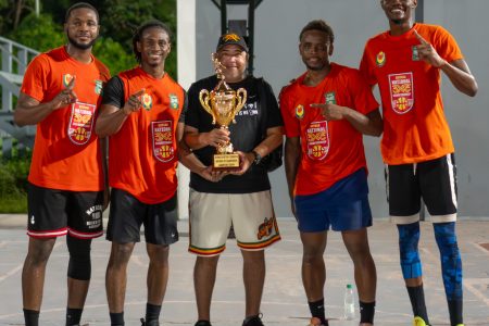 Renegades captain Dominic Vincente (orange) receives the championship trophy from Guyana Basketball Federation President Michael Singh