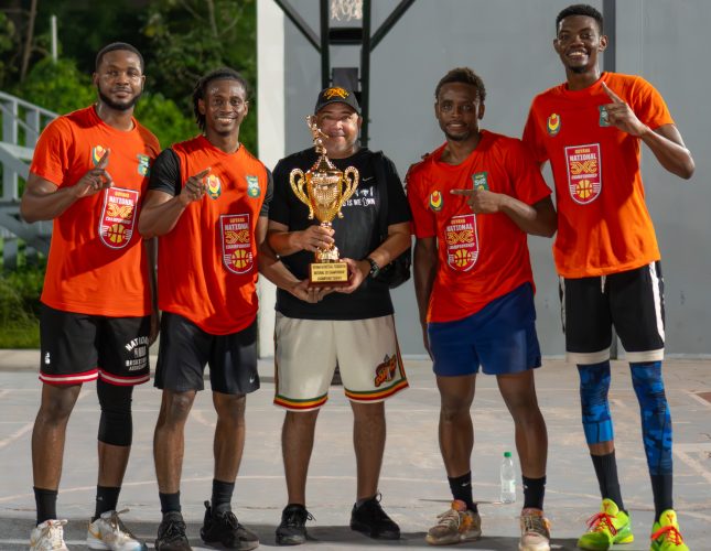 Renegades captain Dominic Vincente (orange) receives the championship trophy from Guyana Basketball Federation President Michael Singh