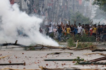 People gesture near smoke as protesters clash with Border Guard Bangladesh (BGB) and the police outside the state-owned Bangladesh Television as violence erupts across the country after anti-quota protests by students, in Dhaka, Bangladesh, July 19, 2024. REUTERS/Mohammad Ponir Hossain