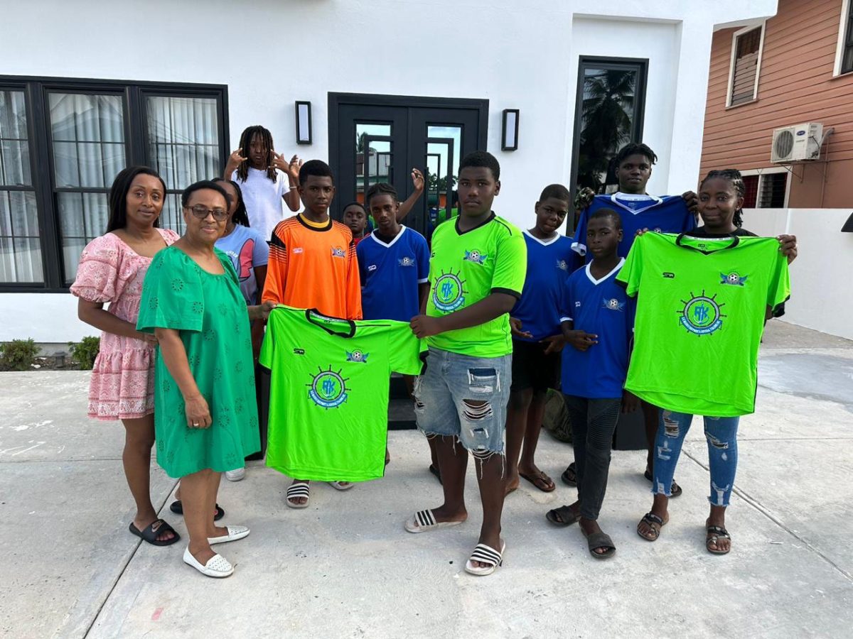 Amabel Clement presents the uniforms to Pouderoyen youth captain Adrian Giddings in the presence of club players and officials
