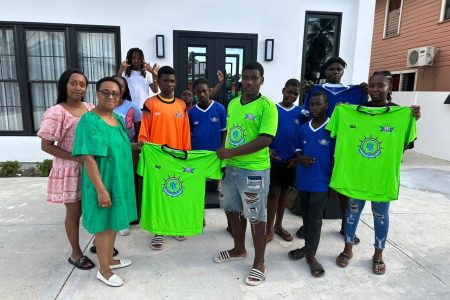 Amabel Clement presents the uniforms to Pouderoyen youth captain Adrian Giddings in the presence of club players and officials
