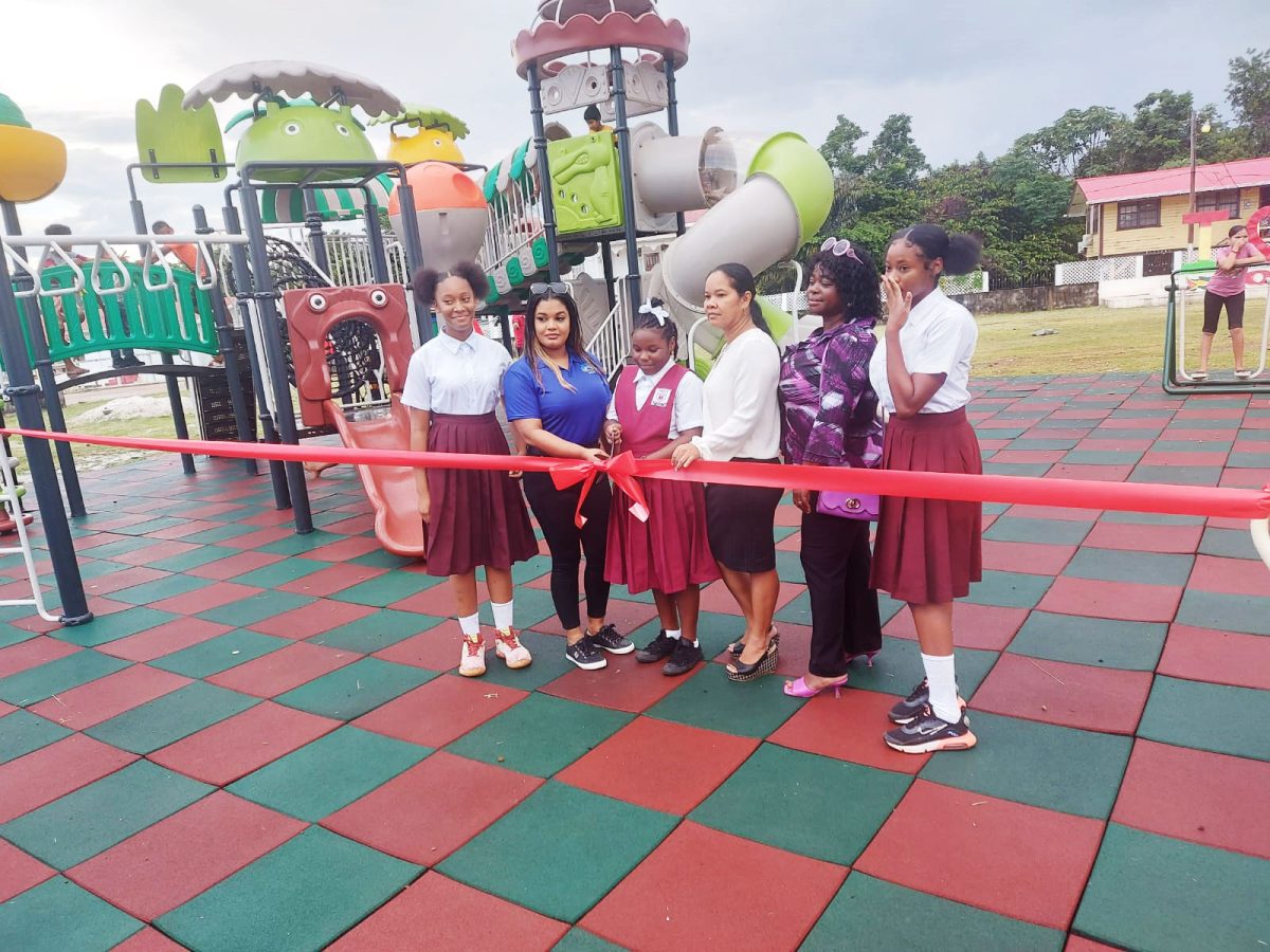 Diana Persaud (second from left), Marketing Manager for Cabana Marketing and Fantasy sports assisting a schoolgirl to cut the ribbon to open the recreational park.  Looking on is Mayor Eslyn Romascindo-Hussain (third from right).