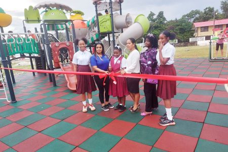 Diana Persaud (second from left), Marketing Manager for Cabana Marketing and Fantasy sports assisting a schoolgirl to cut the ribbon to open the recreational park.  Looking on is Mayor Eslyn Romascindo-Hussain (third from right).