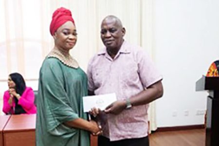 A recipient (left) receiving the Emancipation Grant from Minister of Home Affairs, Robeson Benn (DPI photo)