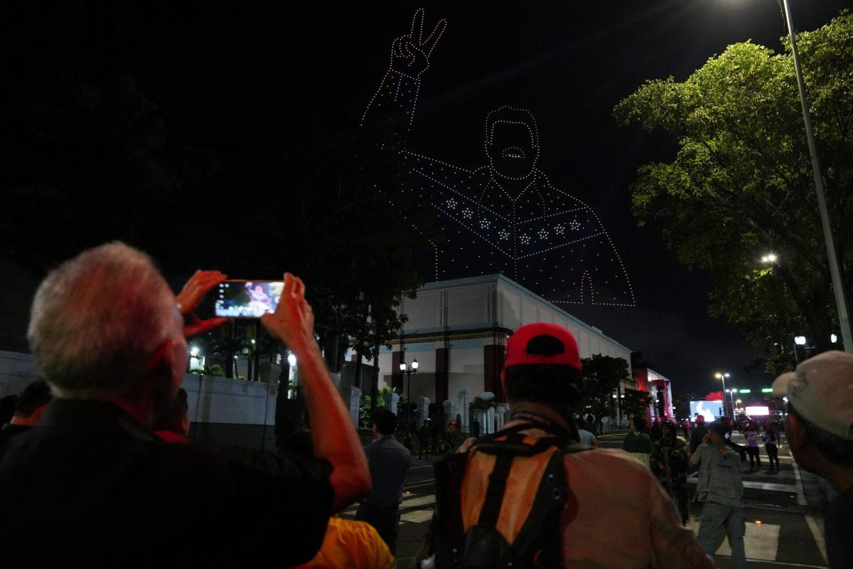 People look at drones creating a display shaped like Venezuelan President Nicolas Maduro showing the victory sign after the electoral authority announced that Maduro had won a third term yesterday. REUTERS/Alexandre Meneghini