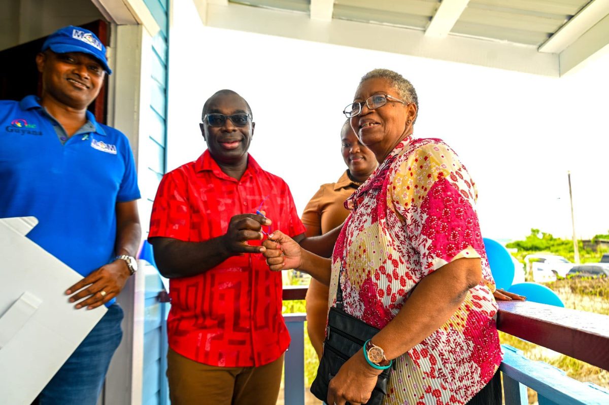 Sandra Hendricks (right), a 70-year-old woman on Sunday received a newly constructed home through the government’s Men on a Mission (MoM) initiative.
Minister within the Office of the Prime Minister with responsibility for Public Affairs, Kwame McCoy (third from right) celebrated the moment with Hendricks. (Department of Public Information photo)
