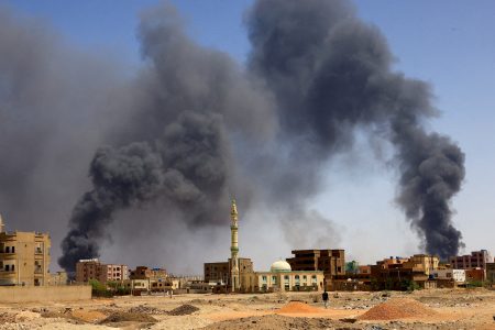 FILE PHOTO: A man walks while smoke rises above buildings after aerial bombardment, during clashes between the paramilitary Rapid Support Forces and the army in Khartoum North, Sudan, May 1, 2023. REUTERS/Mohamed Nureldin Abdallah//File Photo