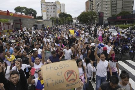 Protesters march against the official election results declaring President Nicolas Maduro the winner, the day after the presidential election in Caracas, Venezuela, Monday, July 29, 2024. The sign reads in Spanish "Until the end. No dictator." (AP Photo/Matias Delacroix)