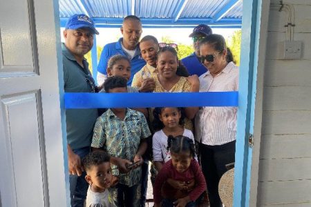 Minister within the Ministry of Public Works, Deodat Indar (left) with the DeYoung family, and the Regional Chairperson,Vilma De Silva (right) cutting the ribbon to open the new home 