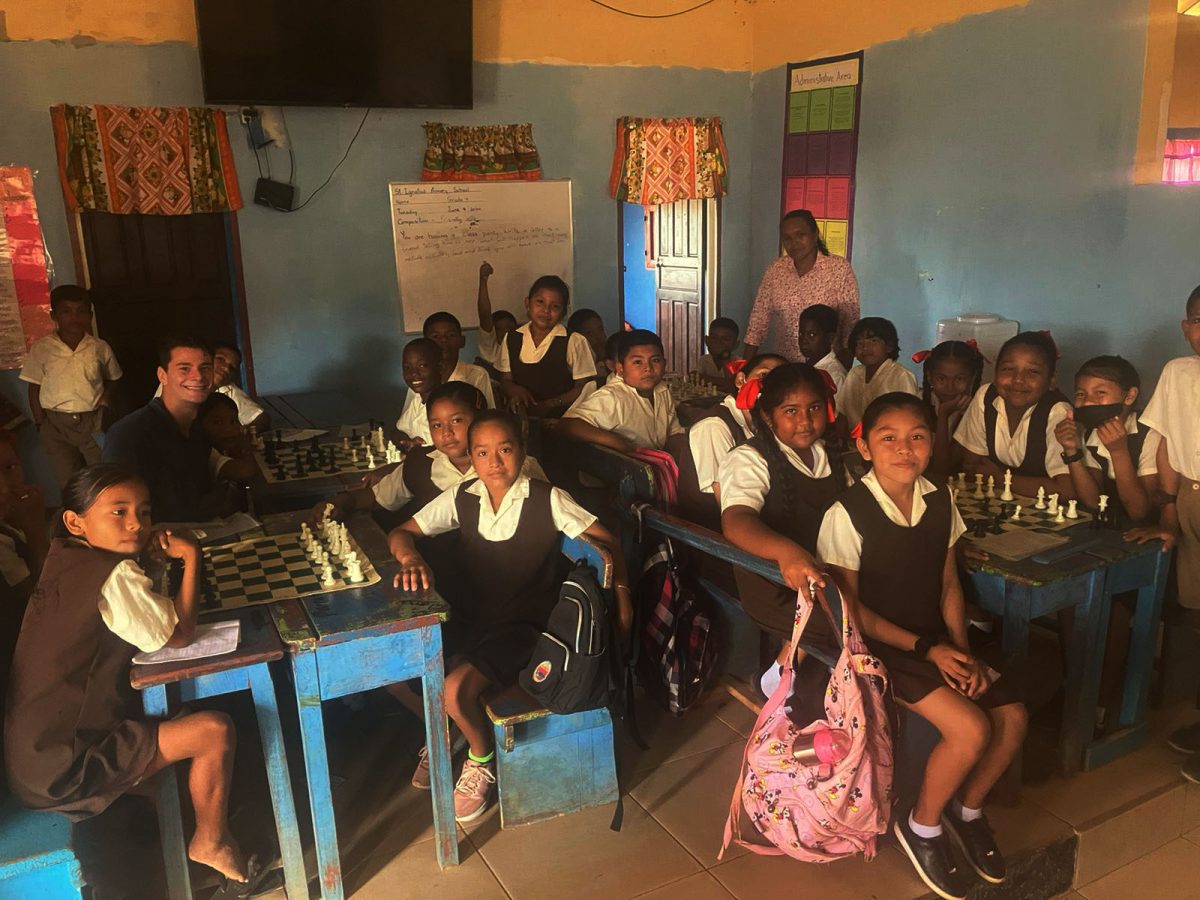 Students of St Ignatius Primary School, Lethem, observing a game of chess being played with one of the new chess sets donated by the Guyana Chess Federation 