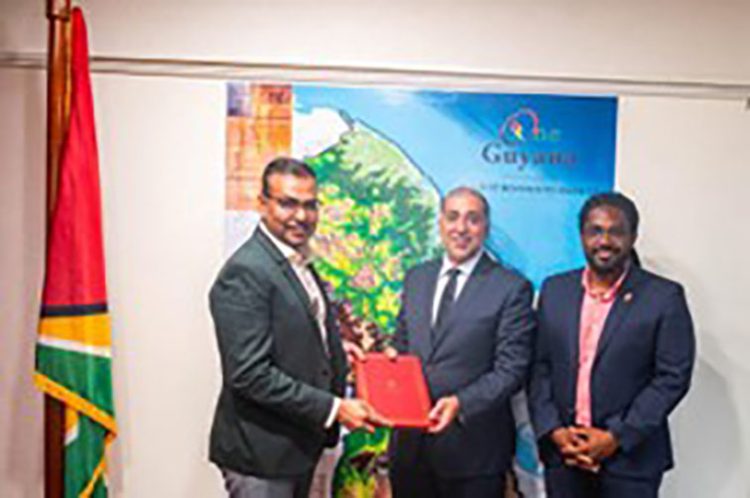 Foreign Secretary and Chairman of the PAC, Robert Persaud (left), along with Acting Charge d’Affaires in the Embassy of the State of Qatar, Mohammed Ebrahim Al Rumai (centre), posing with the signed Agreement as Commissioner, Jason Fraser, looks on