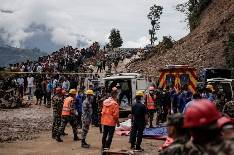 People stranded on the Tribhuwan Highway gather as rescue personnel put the bodies of landslide victims in an ambulance, Dhading, Nepal, September 29, 2024. REUTERS/Navesh Chitrakar