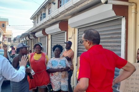 PPP/C councillors Alfonso DeArmas and Don Singh speaking with vendors outside the Kitty market building
