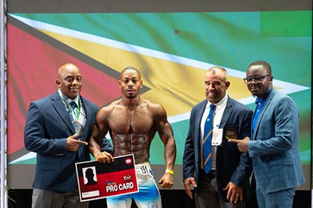 Finally! Emmerson Campbell poses with his Pro Card in the presence of several local and regional officials after winning the Senior Men’s Physique category.
