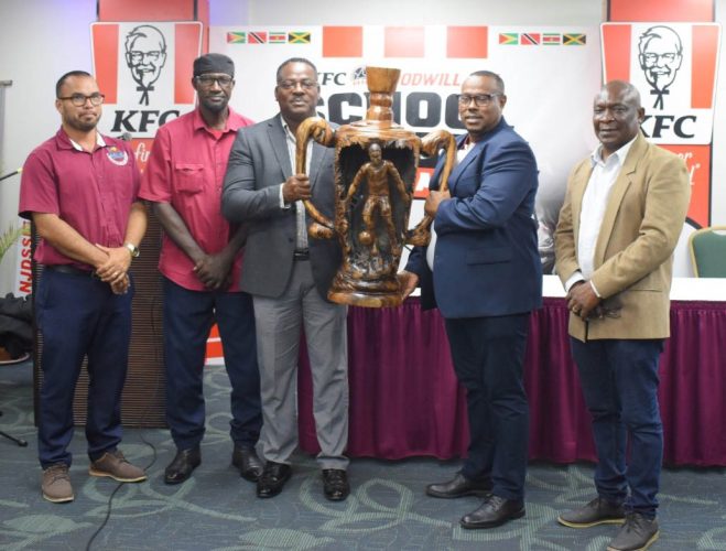 Assistant Director of Sport Franklin Wilson (3rd from left) and Petra Organisation  Co-Director Troy Mendonca (2nd from right) posed  with the trophy at the launch of the KFC Goodwill International School Football competition as other officials looked on.