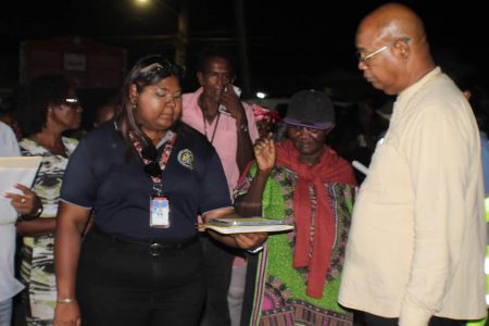 In keeping with a commitment to the vendors of the Plaisance railway embankment, Minister of Public Works, Juan Edghill, along with a team from the Ministry and representatives from the NDC, yesterday handed over 50 vending spots on the newly constructed tarmac.
An additional 19 spots remain vacant and will be handed over by the NDC to more vendors as time progresses, a release from the Ministry of Public Works said. This initiative fulfills a promise made by Vice President  Bharrat Jagdeo to support the smooth progress of the ongoing East Coast Demerara Public Road widening and improvement project while ensuring the livelihoods of local vendors are protected.
In this Ministry of Public Works photo, Minister of Public Works Juan Edghill (right) looks on as a vendor makes her choice.
