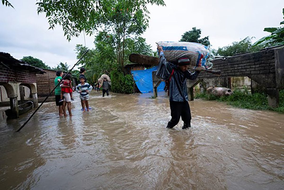 People walk along streets flooded in a community cut off by flooding in the aftermath of tropical storm Sara, in El Marion, Honduras, November 16, 2024.