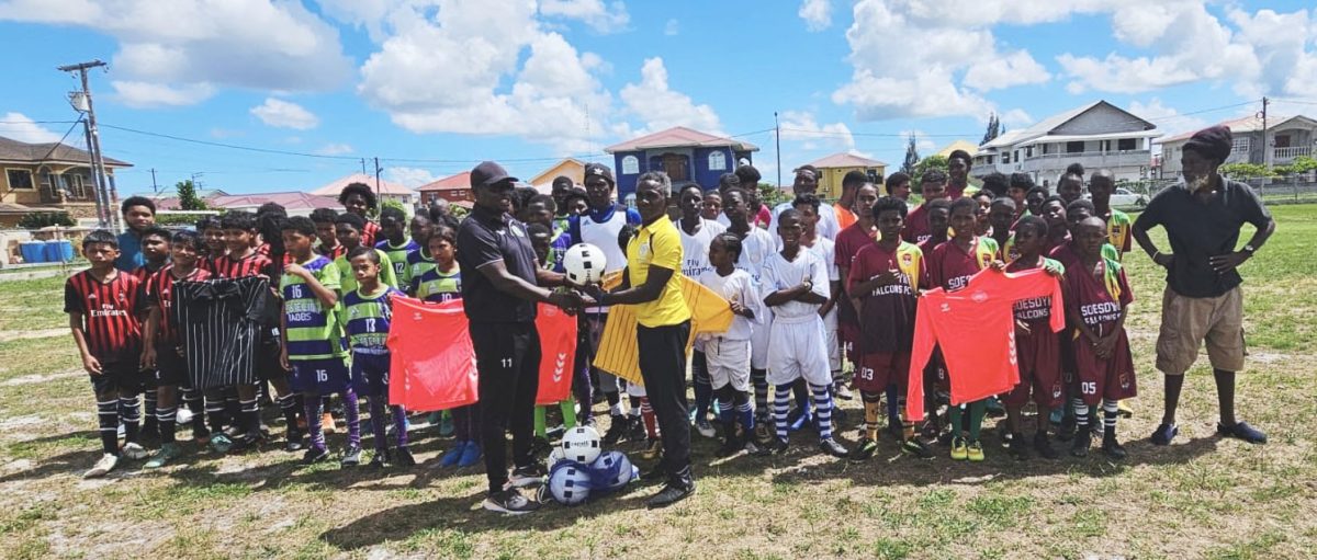 GFF Technical Director Bryan Joseph (left) presents several balls as part of the equipment donation to EBDFA President Orein Angoy in the presence of players from several clubs.