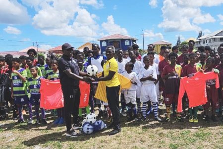 GFF Technical Director Bryan Joseph (left) presents several balls as part of the equipment donation to EBDFA President Orein Angoy in the presence of players from several clubs.