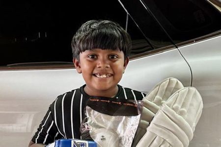 Nine-year-old Aaryan Hooblall poses with some of the cricket gear that was donated to him.
