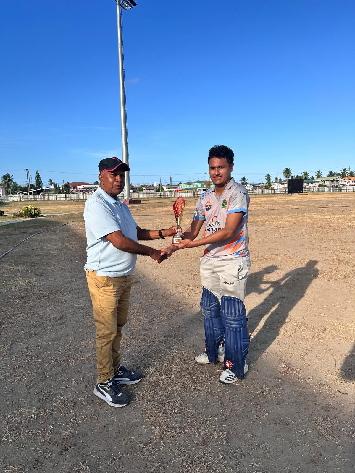 Carlos La Rose (right) collects his Man of the Match award from the match referee. La Rose captured 3/11 and made 23 not out to help the Demerara Hawks to a 7-wicket win over the Berbice Caimans.