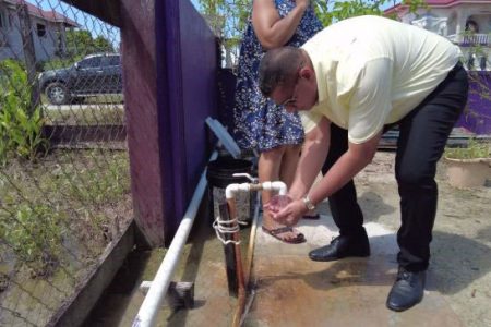 Minister of Housing and Water, Collin Croal takes a sip of water from the tap during an inspection of Parika water quality (DPI photo)