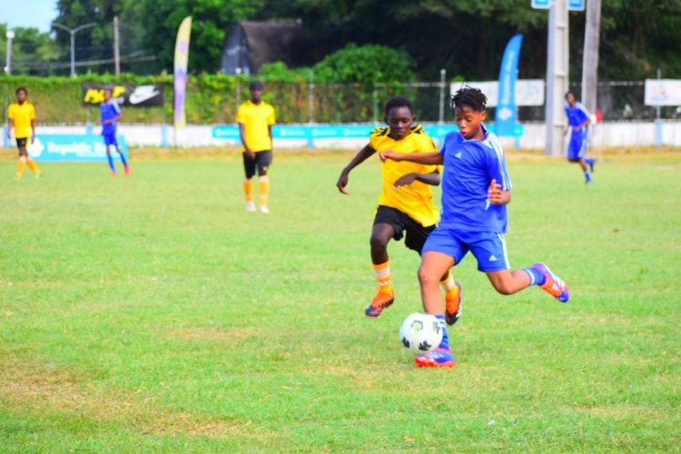 Jaheim Herbert (right) of East Ruimveldt on the attack against West Ruimveldt in the Republic Bank U-18 Schools Football League.