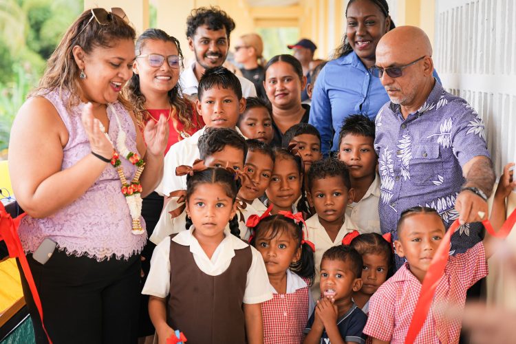 Minister of Education Priya Manickchand (left) at the ribbon-cutting with pupils and others (Ministry of Education photo)