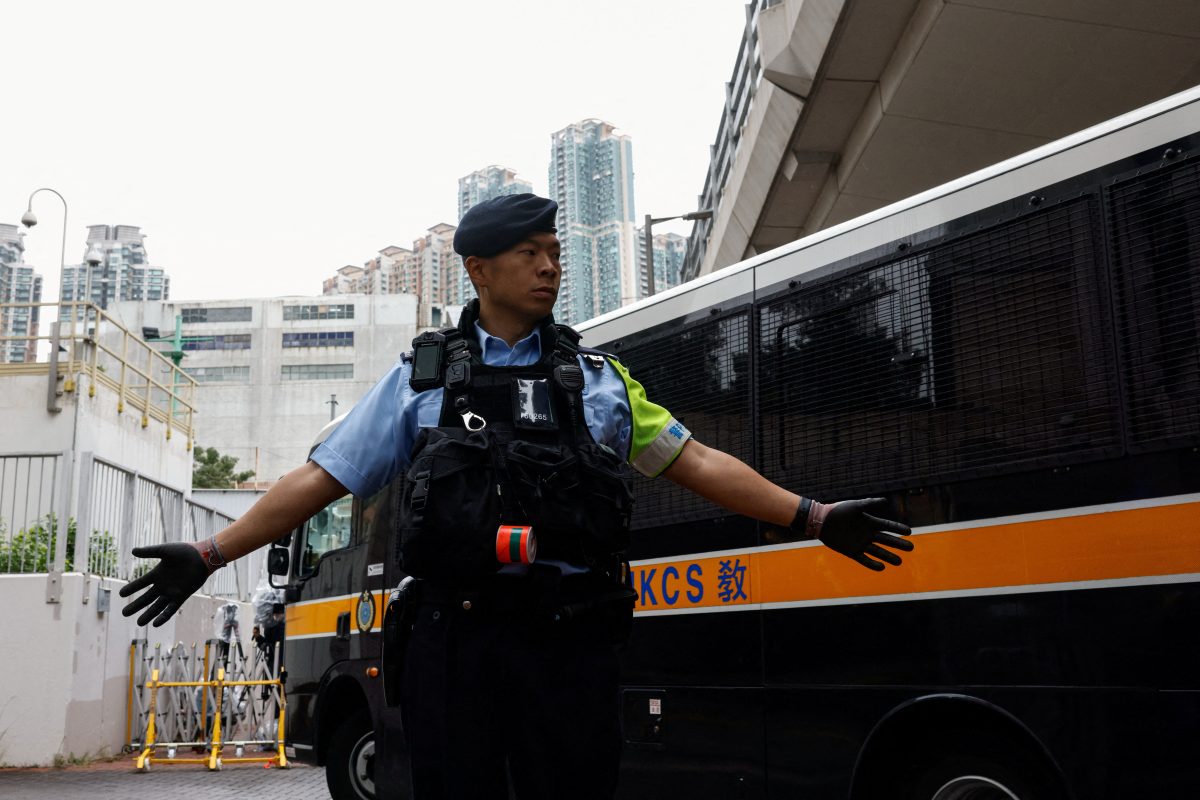 A police officer stands guard as a prison van arrives at the West Kowloon Magistrates’ Courts building, ahead of the sentencing of 45 convicted pro-democracy activists charged under the national security law, in Hong Kong, China November 19, 2024. REUTERS/Tyrone Siu