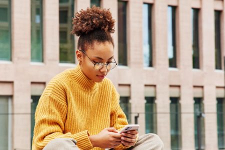 A girl simultaneously using a smartphone and laptop (Image by wayhomestudio on Freepik)
