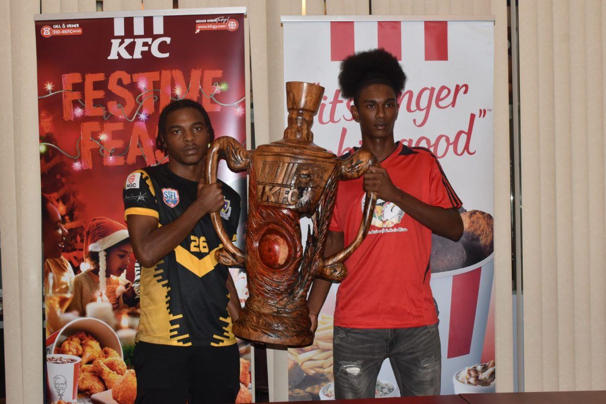 St. Benedict’s College captain Darrel Garcia (left) and Chase’s Academic Foundation skipper Bryan Wharton pose with the brand new KFC Goodwill International trophy ahead of today’s final