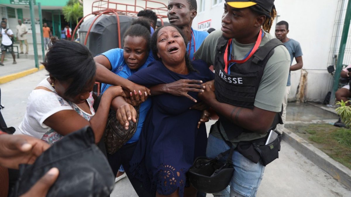 The wife of a journalist, who was shot during an armed gang attack on the General Hospital, cries as an ambulance arrives with his body, at a different hospital in Port-au-Prince, Haiti, Tuesday, Dec. 24, 2024. (AP Photo/Odelyn Joseph)