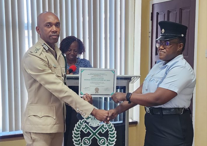 Nicklon Elliot (left) handing over a certificate of achievement.