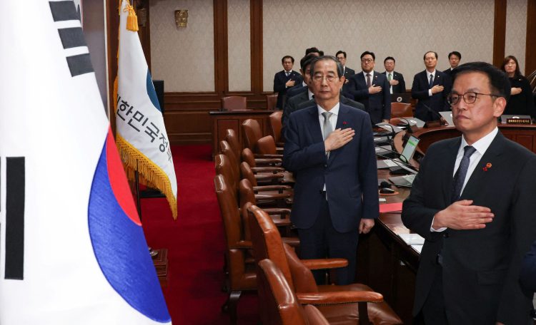 Acting South Korean President and Prime Minister Han Duck-soo salutes to a national flag during a cabinet meeting at the government complex in Seoul, South Korea, December 14, 2024.   Yonhap via REUTERS   THIS IMAGE HAS BEEN SUPPLIED BY A THIRD PARTY. NO RESALES. NO ARCHIVES. SOUTH KOREA OUT. NO COMMERCIAL OR EDITORIAL SALES IN SOUTH KOREA.