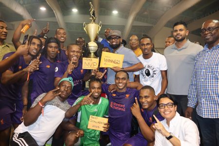 The victorious Sparta Boss unit celebrates as they display their spoils in the presence of President Irfaan Ali (centre) after triumphing in the Kashif and Shanghai National Futsal Championship. Also in the photo are Minister of Culture, Youth, & Sport Charles Ramson Jr. (2nd from right), Minister of within the Ministry of Housing & Water Susan Rodrigues (crouched 1st from right), and Minister of Public Works Juan Edghill (5th from right).
