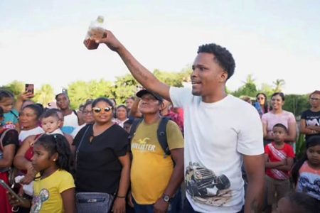 A community member holding up water with an orange hue on Sunday