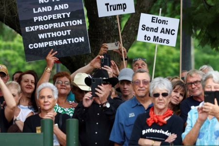 Demonstrators hold placards in support of U.S. President Donald Trump's stance against what he calls racist laws, land expropriation, and farm attacks, outside the American Embassy in Pretoria, South Africa, February 15, 2025. REUTERS/Siphiwe Sibeko