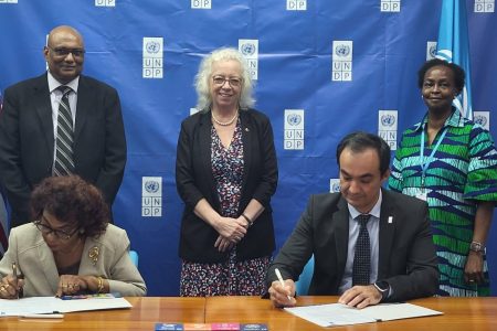 Signing from left to right: are GECOM Chairman, Justice [ret’d] Claudette Singh and UNDP Resident Representative a.i., Berdi Berdiyev. Standing from left to right are:  Chief Election Officer, Vishnu Persaud; British High Commissioner  Jane Miller and United Nations Resident Coordinator, Jean Njeri Kamau.
