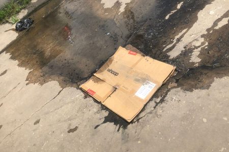 Matter flowing from a manhole on Robb Street, which is covered with a piece of cardboard 