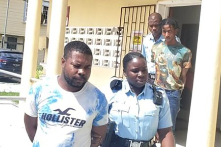 At left, Rayon Frank is being escorted by a policewoman. Behind them, Antwone Campbell (right) is also being escorted by a member of the police force. 