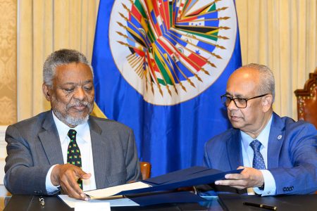 OAS Secretary General Albert Ramdin (right) and Guyana’s Permanent Representative, Samuel Hinds signing the agreement. (OAS photo)