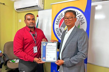 Keon Rankin (left), Head of Certification at the Guyana National Bureau of Standards (GNBS), presents the ‘Made in Guyana’ certification to Chief Executive Officer of the Guyana Sugar Corporation (GuySuCo),  Paul Cheong. (GNBS photo) 