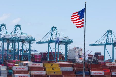 An American flag flutters over a ship and shipping containers at the Port of Los Angeles, in San Pedro California, U.S., May 13, 2025. REUTERS/Mike Blake/File Photo