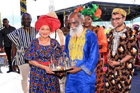 rime Minister Kamla Persad-Bissessar (left) presents Khafra Kambon with an award at African Emancipation Day celebrations at the Lidj Yasu Omowale Village, Queen’s Park Savannah, Port of Spain, yesterday. —Photo: ISHMAEL SALANDY