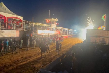 Kishawn Pereira’s riderless horse (right) crossing the finish line after the tragic accident on a rapidly darkening track.